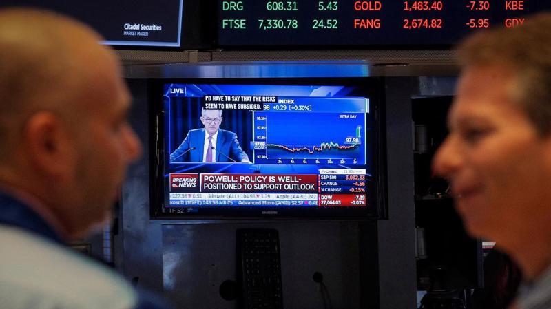 Hai nhà giao dịch trên sàn NYSE ở New York đang theo dõi phát biểu của Chủ tịch FED Jerome Powell phát sóng trực tiếp qua màn hình TV ngày 30/10 - Ảnh: Reuters.