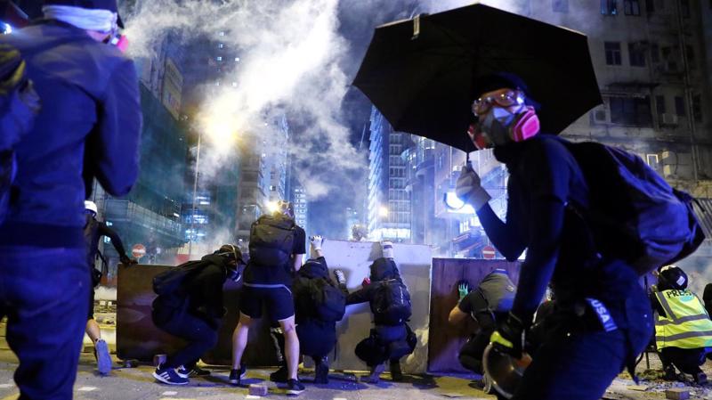 Người biểu tình ẩn nấp khi cảnh sát bắn đạn hơi cay ở khu Mong Kok của Hồng Kông ngày 11/11 - Ảnh: Reuters.