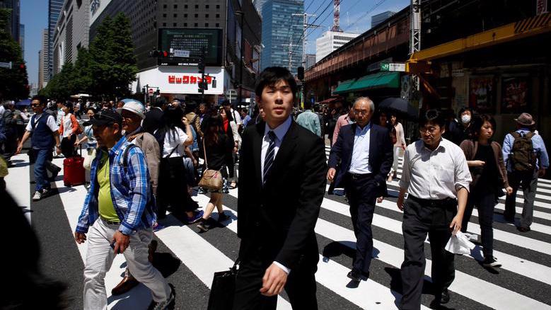 Người bộ hành trên đường phố ở quận kinh doanh trung tâm Tokyo - Ảnh: Reuters.