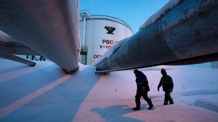 Hai công nhân đi ngang qua những đường ống dẫn dầu ở một cơ sở dầu lửa của Nga hồi tháng 1/2014 - Ảnh: Getty/CNBC.