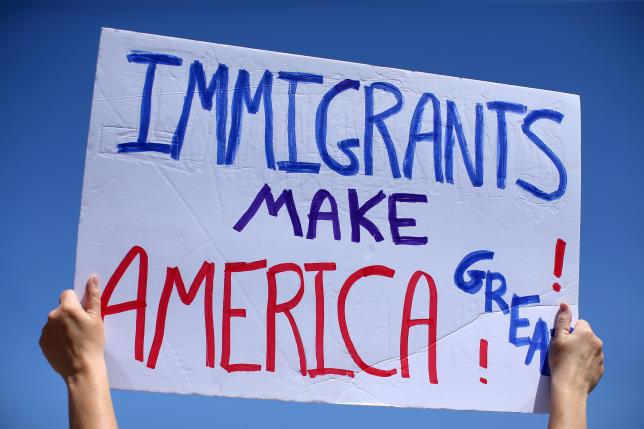 Một nhà hoạt động bảo vệ người nhập cư giơ biểu ngữ ở San Diego, California, hôm 21/4 - Ảnh: Reuters.<br>