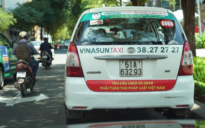 Mới đây, hàng loạt taxi của hãng treo khẩu ngữ đòi Uber, Grab phải "tuân thủ pháp luật Việt Nam", và đã tháo gỡ sau khi có nhiều chỉ trích hành động này từ dư luận - Ảnh: Tuổi Trẻ.