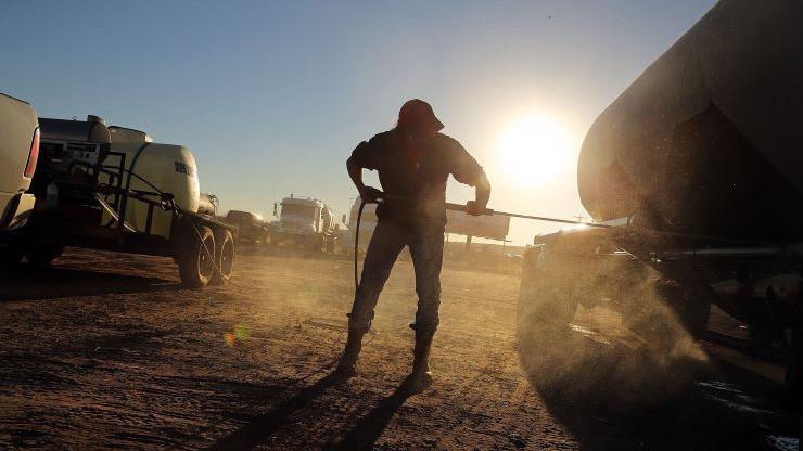 Một người công nhân đang làm việc bên những chiếc xe chở dầu tại một mỏ dầu ở Odessa, Texas - Ảnh: Getty/CNBC.