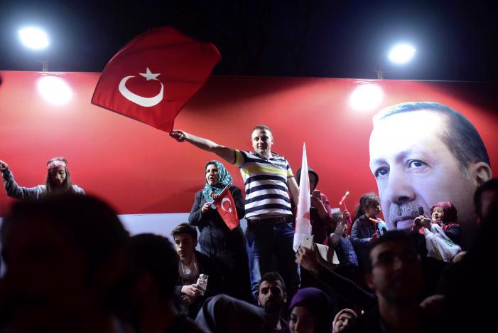 Người ủng hộ Tổng thống Thổ Nhĩ Kỳ Tayip Erdogan ăn mừng chiến thắng bên cạnh một tấm ảnh lớn của ông ở Istanbul ngày 16/4 sau khi có kết quả trưng cầu dân ý - Ảnh: Reuters.<br>