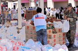 Binh sĩ Chile và nhân viên tình nguyện đóng gói thực phẩm phân phát cho các nạn nhân động đất - Ảnh: AFP.