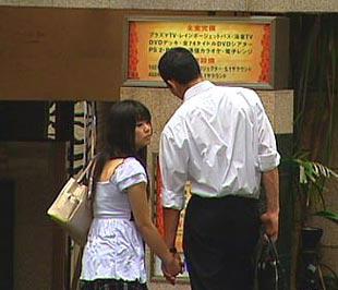 Một cặp đôi trẻ tuổi trước cửa một khách sạn tình yêu ở Tokyo.