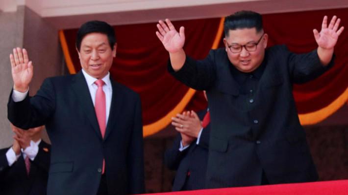Chủ tịch Quốc hội Trung Quốc Lật Chiến Thư (trái) và nhà lãnh đạo Triều Tiên Kim Jong Un (phải) vẫy chào từ khán đài trong lễ duyệt binh - Ảnh: Reuters.