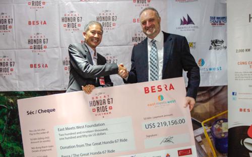 Ông David Seton, Chủ tịch Công ty Besra, trao 219.156 USD quyên góp được từ "Hành trình Honda 67" cho ông Tom Low, Giám đốc Tài chính của tổ chức Đông Tây Hội Ngộ 