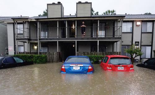 Một người dân thành phố Houston&nbsp;đứng trên tầng 2 khu nhà của mình nhìn ra ngoài trời mưa lũ -&nbsp;Ảnh: NBCNews.