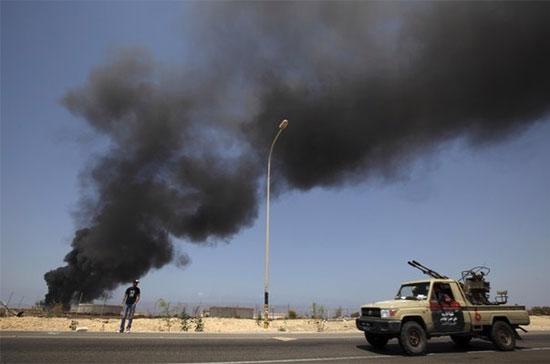 Lửa cháy bên ngoài một kho xăng tại Brega, Libya. Nội chiến tại nước này đã tác động đáng kể đến diễn biến giá nhiên liệu trên thị trường thế giới trong năm 2011 - Ảnh: Reuters.