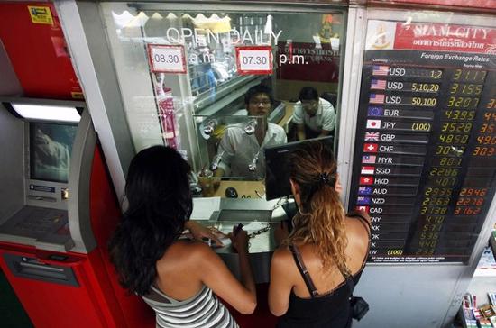 Khách du lịch đang đổi tiền ở ngân hàng tại Bangkok, Thái Lan - Ảnh: Reuters.