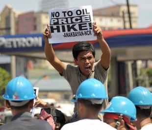 Một người biểu tình giơ cao biểu ngữ phản đối giá dầu cao, phía trước một cửa hàng xăng dầu tại thủ đô Manila (Philippines), ngày 22/6 - Ảnh: Getty Images.