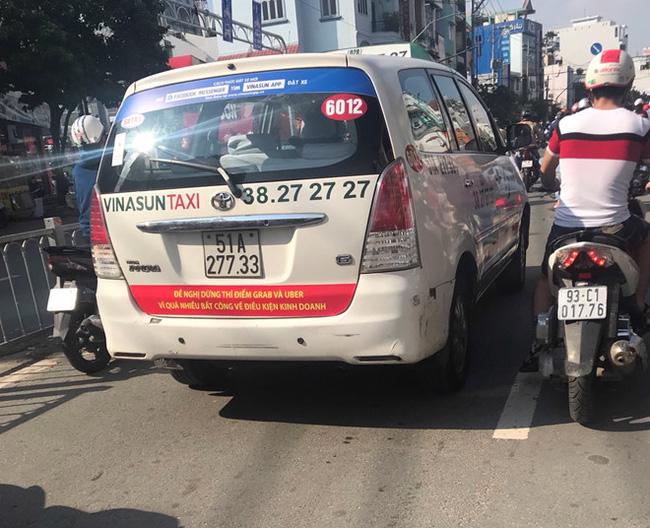 Một chiếc Taxi của hãng Vinasun dán dòng chữ: "Yêu cầu Uber và Grab phải tuân thủ pháp luật Việt Nam" và “Đề nghị dừng thí điểm Grab và Uber vì quá nhiều bất công về điều kiện kinh doanh”.<br>