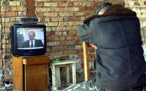 Một người dân Ukraine lắng nghe bài phát biểu của Tổng thống Nga Putin về việc tiếp nhận Crimea trên truyền hình - Ảnh: Reuters.<br>