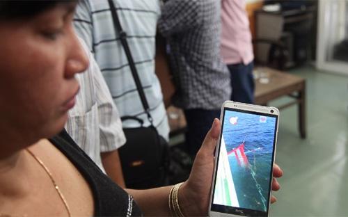 Bà Huỳnh Thị Như Hoa cho phóng viên CNN xem hình ảnh con tàu cá bị chìm - Ảnh: CNN.<br>