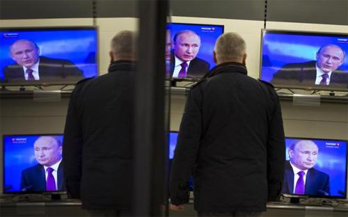Một người đàn ông xem Tổng thống Nga Vladimir Putin phát biểu trên TV, tại một siêu thị điện máy ở Moscow hôm 18/12 - Ảnh: AP.<br>