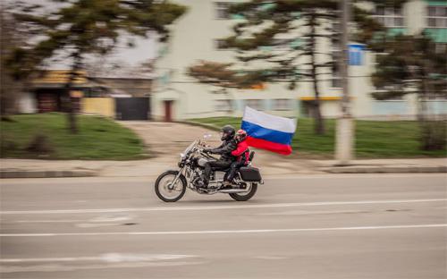 Xe máy cắm cờ Nga chạy trên đường phố Crimea, hôm 10/3 - Ảnh: Sergii Morgunov.<br>