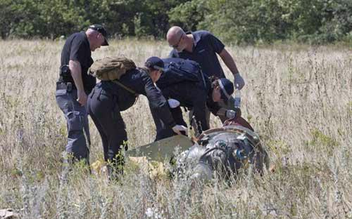 Các chuyên gia Australia tiếp cận một mảnh vỡ của máy bay MH17 - Ảnh: AP.