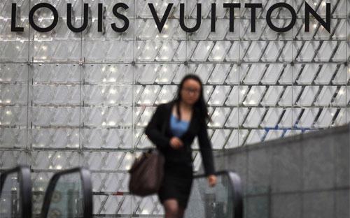 Một phụ nữ đi qua một cửa hiệu Louis Vuitton ở Thượng Hải, Trung Quốc - Ảnh: Reuters/BI.<br>