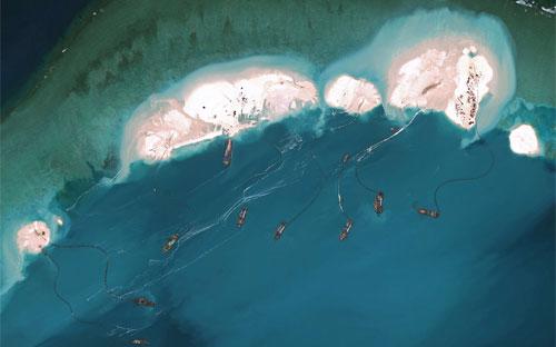 Ảnh chụp từ vệ tinh hôm 16/3/2015 cho thấy tàu hút cát của Trung Quốc đang bồi lấp bãi đá Vành Khăn thuộc quần đảo Trường Sa - Ảnh: DigitalGlobe/Getty/Bloomberg.<br>