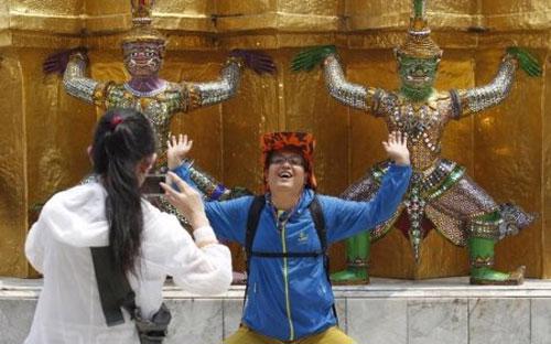 Du khách Trung Quốc tạo dáng để chụp ảnh khi thăm một cung điện ở Bangkok, Thái Lan - Ảnh: Reuters/BI.<br>