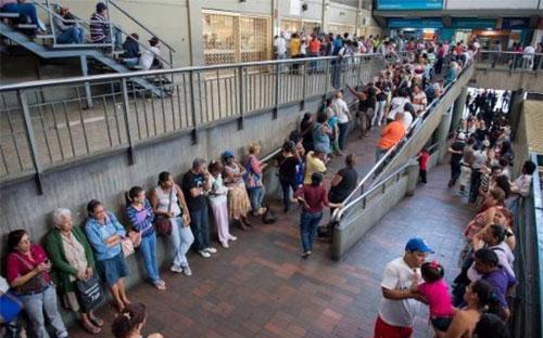 Người dân Venezuela xếp hàng chờ mua hàng hóa thiết yếu bên ngoài một siêu thị ở thủ đô Caracas.<br>