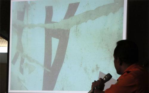 Một nhà tìm kiếm Indonesia đưa ra bức ảnh một mảnh vỡ của chuyến bay 8501 dưới đáy biển Java - Ảnh: AP/WSJ.<br>