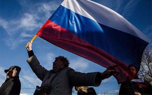 Người Crimea vẫy cờ Nga trong dịp một năm bán đảo này ly khai khỏi Ukraine và gia nhập Nga - Ảnh: Getty/Bloomberg.<br>
