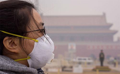 Một cô gái đeo khẩu trang để đối phó với bầu không khí ô nhiễm ở thủ đô Bắc Kinh, Trung Quốc - Ảnh: Getty.<br>