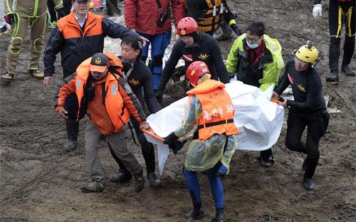 Nhân viên cứu hộ di chuyển thi thể một nạn nhân máy bay TransAsia rơi ở Đài Bắc được tìm thấy ngày 6/2 - Ảnh: AP/WSJ.<br>