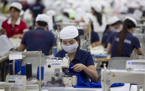 Công nhân làm việc trong nhà máy sản xuất hàng may mặc của công ty Esquel Group ở Thuận An, Bình Dương - Ảnh: Bloomberg.<br>