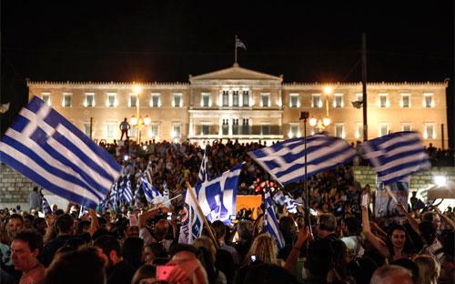 Người dân Hy Lạp ủng hộ việc bỏ phiếu chống trong cuộc trưng cầu dân ý ngày 5/7 tập trung trước cửa tòa nhà Quốc hội ở Athens đêm cùng ngày - Ảnh: Bloomberg.<br>