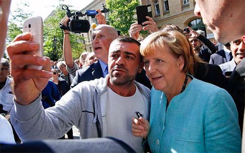 Một người di cư chụp ảnh với Thủ tướng Đức Angela Merkel. Bà Merkel được coi là nhà lãnh đạo châu Âu "hảo tâm" nhất với người di cư - Ảnh: Reuters.<br>