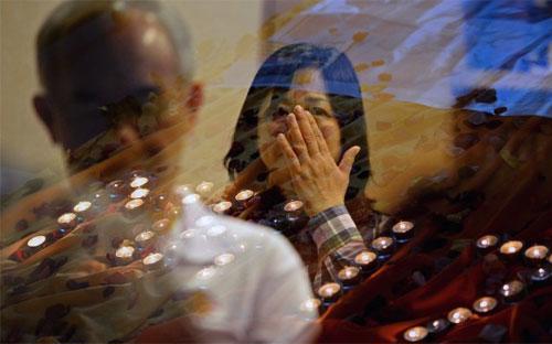 Nhiều người cầu nguyện cho các nạn nhân trên chuyến bay MH17 của Malaysia Airlines bên ngoài một nhà thờ ở Kuala Lumpur, Malaysia - Ảnh: AP.