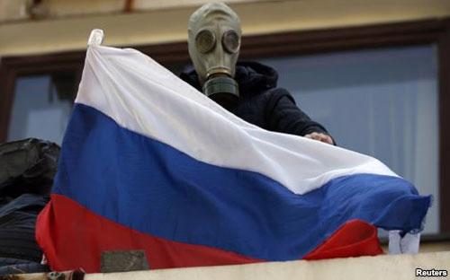 Dân quân thân Nga đeo mặt nạ chống hơi độc đứng trên ban công hội trường thành phố ở Mariupol, miền đông Ukraine.