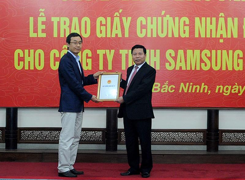 Chủ tịch UBND tỉnh Bắc Ninh, ông Nguyễn Nhân Chiến (phải) trao giấy phép cho đại diện Samsung Display<br>