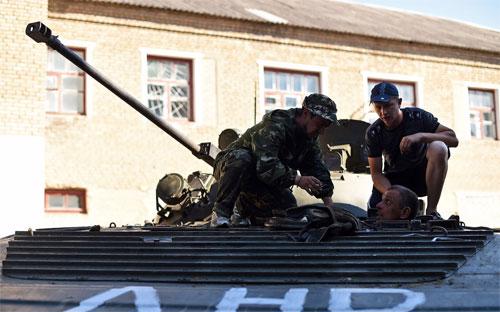 Các phần tử nổi dậy Ukraine đang sửa một xe tăng do quân chính phủ bỏ lại ở Komsomolske, gần Donetsk - Ảnh: AFP/Getty/Bloomberg.<br>