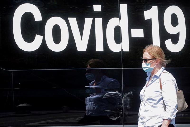 Một phụ nữ đeo khẩu trang đi ngang qua xe tải xét nghiệm Covid-19 di động tại Công viên Quảng trường Washington tại New York, Mỹ ngày 22/7 - Ảnh: Reuters