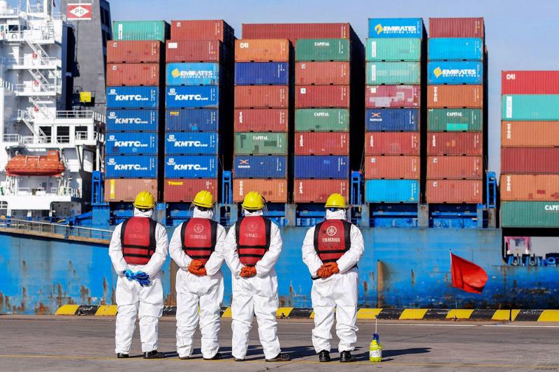 Các công nhân cảng biển trong trang phục bảo hộ ở Thanh Đảo, Trung Quốc hôm 14/1 - Ảnh: Getty/Bloomberg.