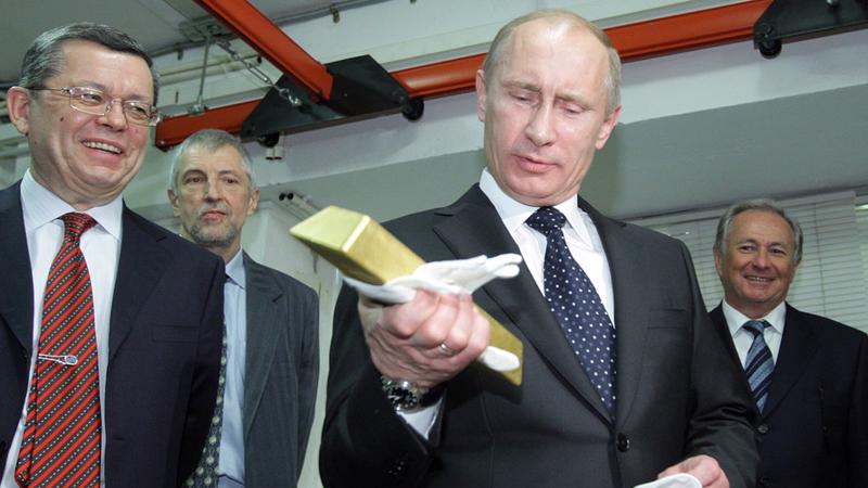 Tổng thống Nga Vladimir Putin cầm một thỏi vàng trong chuyến thăm Kho lưu ký Trung ương của Ngân hàng Trung ương Nga khi ông còn là thủ tướng vào tháng 1/2011 - Ảnh: AFP