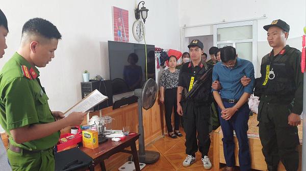 Bị can Phạm Trung Kiên (áo xanh than) nghe đọc lệnh khám xét khẩn cấp tại nhà riêng