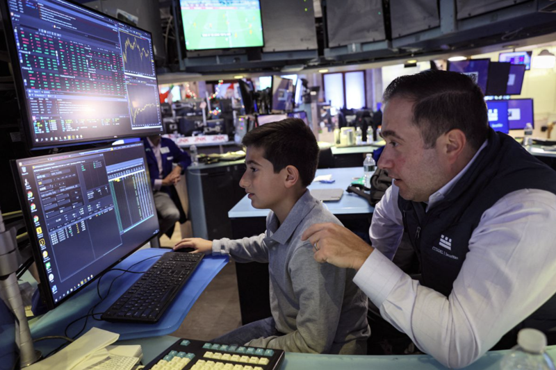 Một nhà giao dịch trên sàn NYSE  đưa con trai tới nơi làm việc theo truyền thống hàng năm của sàn này, hôm 25/11 - Ảnh: Reuters.