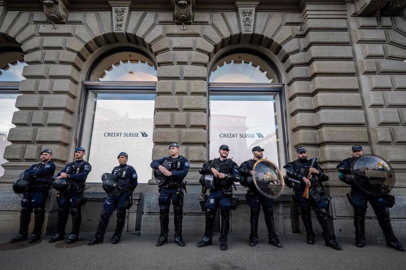Cảnh sát chống bạo động đứng trước trụ sở của Credit Suisse sau thông báo về thương vụ giải cứu - Ảnh: Getty Images
