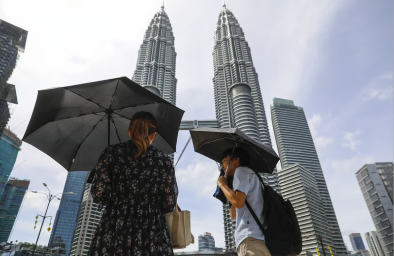 Một cặp đôi dùng ô che nắng trong một ngày nắng nóng ở Kuala Lumpur vào tháng trước - Ảnh: EPA-EFE