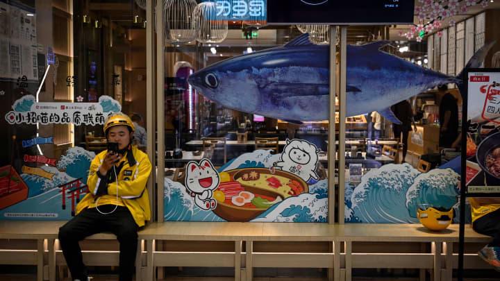 Nhân viên giao đồ ăn ngồi bên ngoài một nhà hàng tại một trung tâm mua sắm ở Bắc Kinh vào ngày 30/5/2023 - Ảnh: Getty Images