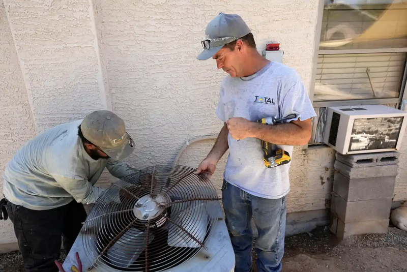 Ông Michael Villa và JP Lantin, thợ sửa chữa điều hòa tại ngôi nhà ở Laveen, bang Arizona - Ảnh: AP.