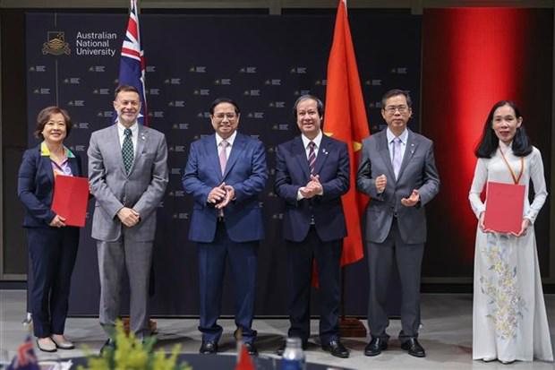 Prime Minister Pham Minh Chinh (third, left) witnesses the exchange of cooperation documents between Vietnamese and Australian universities. (Photo: VNA)