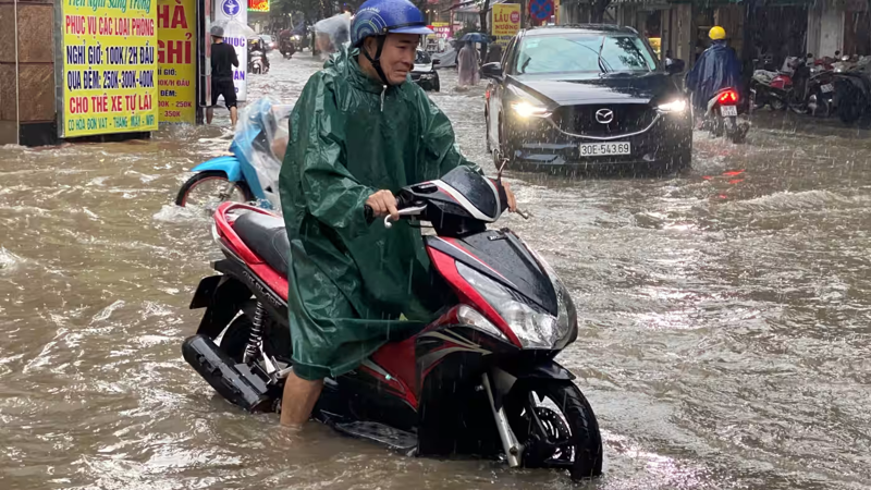 Một người đàn ông lái xe máy trên đường phố bị ngập ở Hà Nội sau trận mưa lớn vào tháng 9/2023 - Ảnh: Reuters