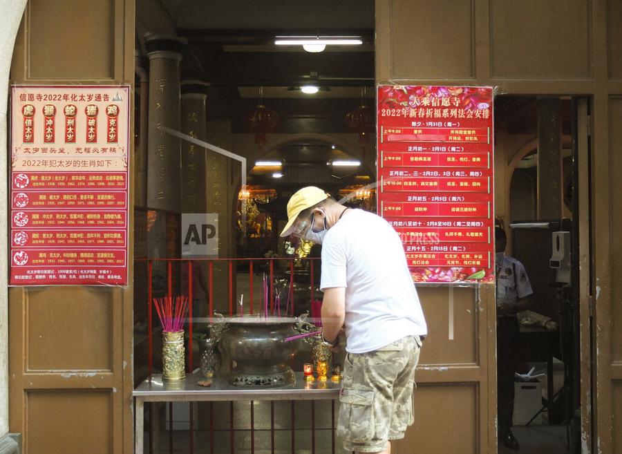 Một người đ&agrave;n &ocirc;ng thắp hương b&ecirc;n ngo&agrave;i một ng&ocirc;i đền của người Trung Quốc tại Manila, Philippines - Ảnh: AP