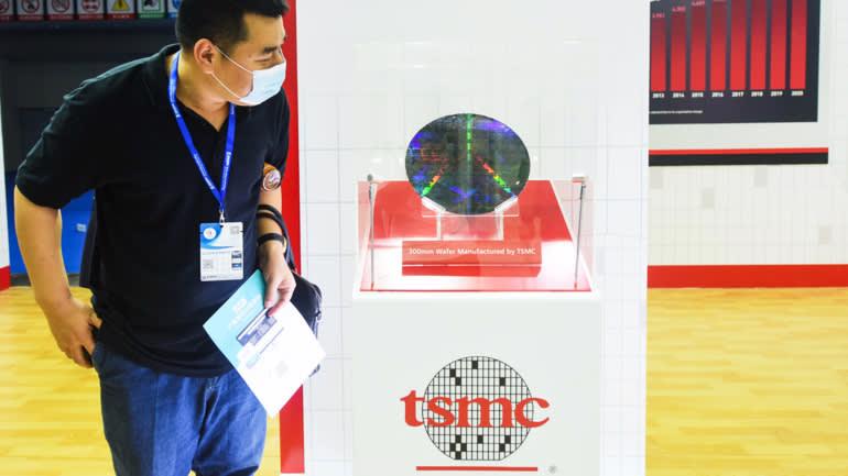 Một kh&aacute;ch tham quan xem tấm b&aacute;n dẫn (wafer) 300mm trong gian h&agrave;ng của TSMC tại một hội chợ thương mại ở Trung Quốc năm 2021 - Ảnh: Getty Images